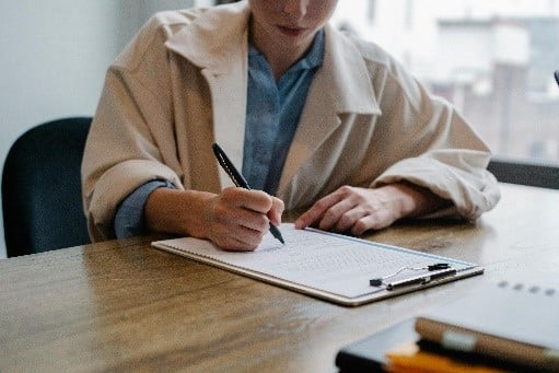 Person schreibt Notizen auf einem Clipboard