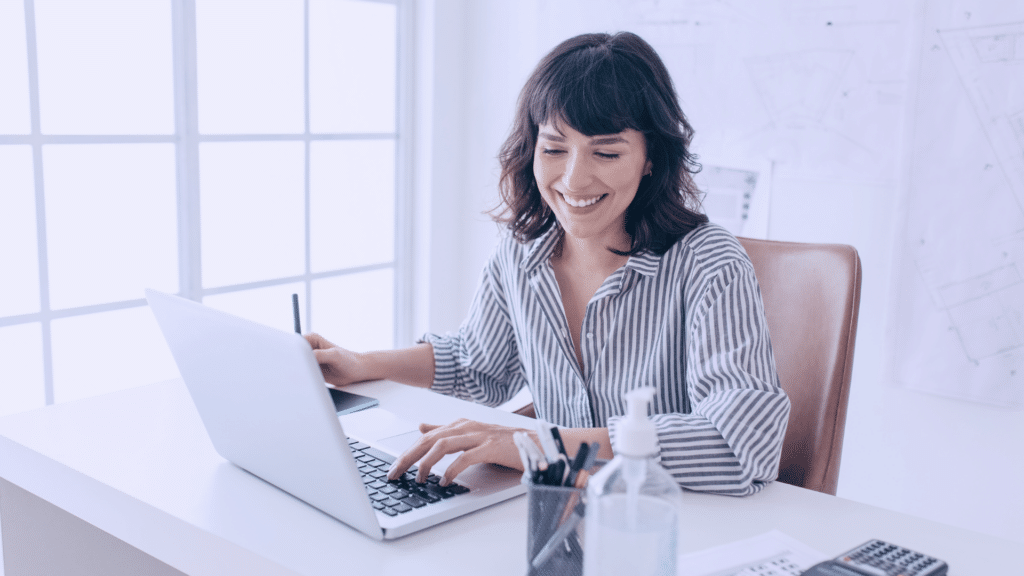 Frau arbeitet lächelnd am Laptop im Büro