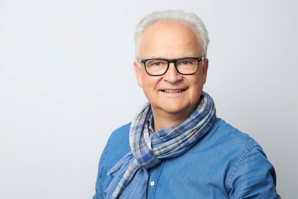 Mann mit Brille und Schal lächelt