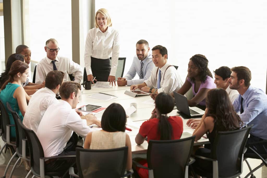 Teammeeting im Konferenzraum mit stehender Leiterin
