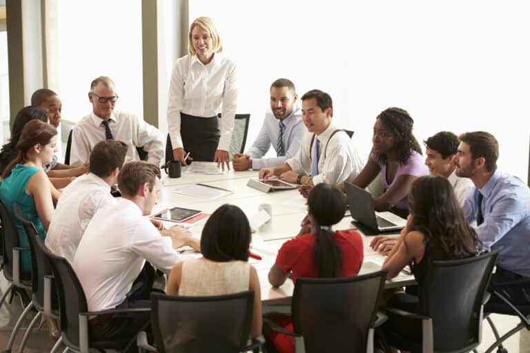 Teammeeting im Konferenzraum mit stehender Leiterin