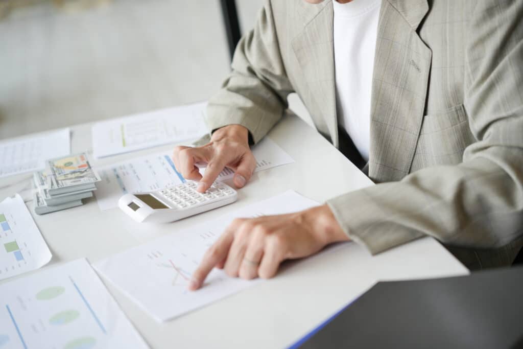 Person berechnet Finanzen mit Taschenrechner am Schreibtisch